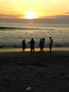 un grupo de personas de pie en la playa al atardecer en Alquiler casa completa, Puerto Cayo, hermosa vista, en Puerto Cayo