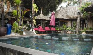 a swimming pool with pink chairs and an umbrella at Joe's Cafe & Garden Resort in Mui Ne