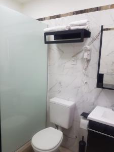 Baño blanco con aseo y lavamanos en Departamentos PEUQUE en Comodoro Rivadavia