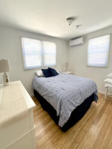a bedroom with a bed and two windows at Lbi Vacation Rental Property in Beach Haven
