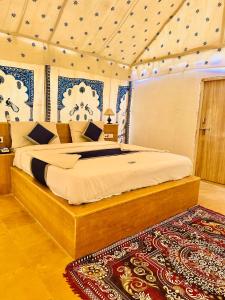 una camera con un grande letto in una stanza con un tappeto di Best Desert Camp In Jaisalmer Red Velvet a Jaisalmer