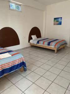 Habitación con 2 camas y suelo de baldosa. en HOTEL PUERTO REAL SUITES, en Paraíso