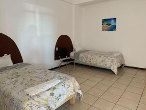 Un dormitorio con 2 camas y una silla. en HOTEL PUERTO REAL SUITES, en Paraíso