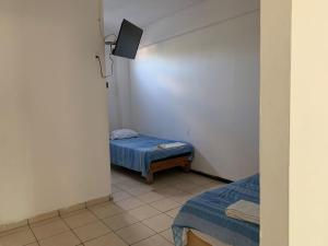 een kleine kamer met 2 bedden en een televisie bij HOTEL PUERTO REAL SUITES in Paraíso