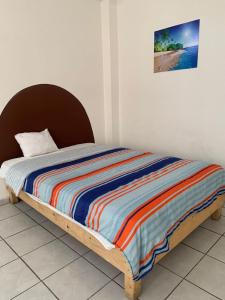 uma cama com um edredão listrado colorido num quarto em HOTEL PUERTO REAL SUITES em Paraíso