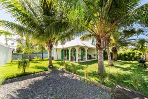 a house with palm trees in front of it at Villa à la Plage, lagon à 500m, climatisée in Saint-Paul