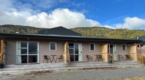 a house with chairs and tables in front of it at The Crossing Lodge & Backpackers in Erua