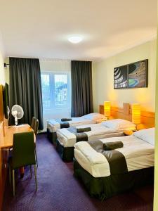 a hotel room with four beds and a table at Słupsk forest - PREMIUM APARTAMENTS - Kaszubska street 18 - Wifi Netflix Smart TV50 - pleasure quality stay in Słupsk