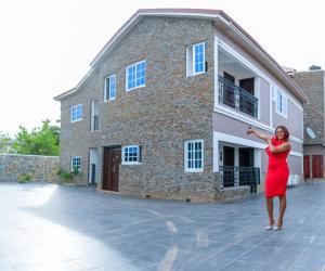 een vrouw in een rode jurk die voor een gebouw staat bij Douglas Court Accra-Fantastic Living 1,2,3-Beds in Adenta, 5star Service, Free Wifi, 30mins to Airport, by DLA 