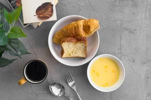 a table with a plate of bread and a bowl of soup at &AND HOSTEL SHINSAIBASHI EAST in Osaka