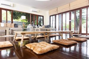 ein Wohnzimmer mit einem Holztisch und großen Fenstern in der Unterkunft Hide & Seek River Villa in Ban Wang Wa (1)