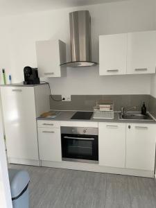 een witte keuken met een fornuis en een wastafel bij Appartement t2 avec terrasse et cour in Cavaillon
