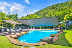 a swimming pool in a yard with a mountain in the background at Lagoon Beachfront Lodge 206 on Hamilton Island by HamoRent in Hamilton Island