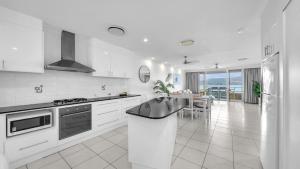 a white kitchen with a sink and a stove at Lagoon Beachfront Lodge 206 on Hamilton Island by HamoRent in Hamilton Island