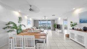 a dining room and living room with a table and chairs at Lagoon Beachfront Lodge 206 on Hamilton Island by HamoRent in Hamilton Island