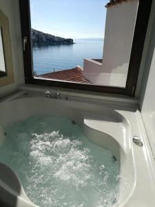 a bath tub with a view of the ocean from a window at Beach house BellaVista with hot pool in Trogir