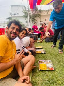 un groupe de personnes assises sur l'herbe qui mangent de la nourriture dans l'établissement Lifespace Rishikesh- Hotel, Hostel, Cowork, Cafe, à Rishikesh