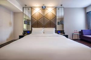 a bedroom with a large white bed and a blue couch at Spey Hotel - Foshan Ancestral Temple Subway Station in Foshan