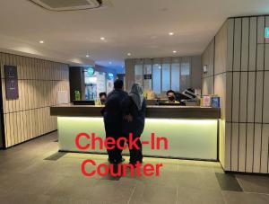 a couple standing at the counter of a check in counter at Ceylonz Suites KL Tower View Bukit Bintang in Kuala Lumpur