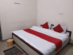 1 cama con sábanas rojas y blancas y almohadas rojas en Vamoose Govind en Rudraprayāg