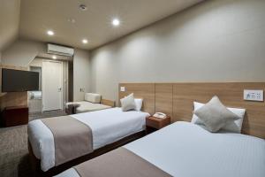 Hotel Villa Fontaine Tokyo-Jimbocho في طوكيو: غرفة فندقية بسريرين وتلفزيون بشاشة مسطحة