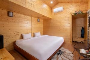 a bedroom with a white bed in a wooden room at Tam Coc Friends Bungalow Ninh Bình in Ninh Binh