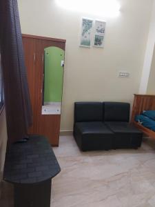 a living room with a black couch and a green door at New greens inn in Yelagiri