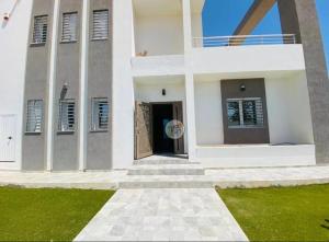 biały budynek z drzwiami i trawnikiem w obiekcie villa jassem w mieście Awlād ‘Umar