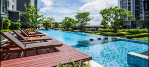 a large swimming pool with lounge chairs in a building at Rooms bangkok nearby Onnut bts in Amphoe Phra Khanong