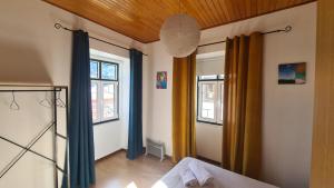 a bedroom with two windows and blue curtains at Arcadas da Vila in Manteigas