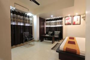 a bedroom with a bed and a chair and a desk at Hotel Rashmi Guwahati in Guwahati