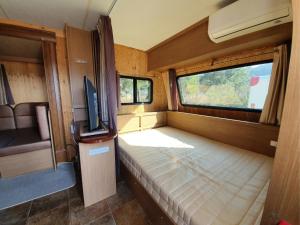 Byeonsan Auto Camping في بوان: غرفة صغيرة فيها سرير وتلفزيون