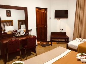 a hotel room with a desk and a bedroom at Marigold Home in Nuwara Eliya
