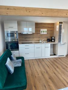 a kitchen with white cabinets and a green couch at Bruchersee 4 oberbergisches Land in Marienheide