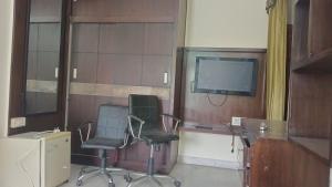 - une chambre avec 2 chaises et une télévision dans l'établissement raminder singh ghai, à Jaipur