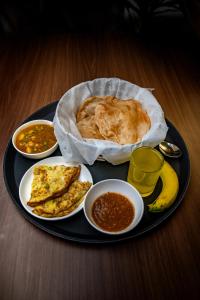 Muscatel Fairmont – 100 Mts from Mall Road في دارجيلنغ: طبق أسود من الطعام مع طعام الإفطار على الطاولة