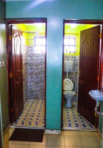 a bathroom with two doors and a toilet and a sink at S & A APARTMENTS in Thika