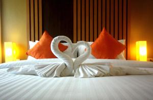 two white swansuitsrendered to look like they are kissing on a bed at Breezotel - SHA Certified in Patong Beach