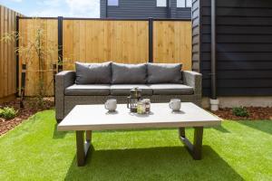 un patio con sofá y una mesa sobre hierba en Urban Escape Ground Floor Studio, Wilmer St, en Christchurch