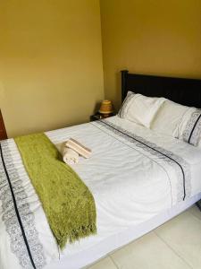 Una cama blanca con una manta verde. en Good and Proper Guest Lodge, en Vereeniging