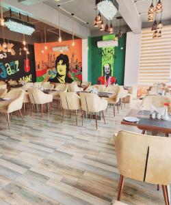 una sala da pranzo con tavoli, sedie e un murale di Hotel Golden Palm a Patna