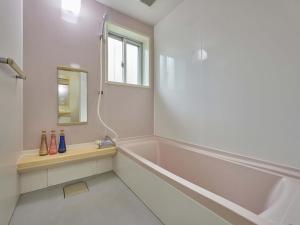a white bathroom with a tub and a mirror at Yukurina Resort Okinawa in Motobu