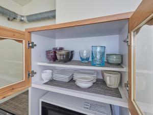 a cupboard with bowls and other ceramics in it at Yukurina Resort Okinawa in Motobu