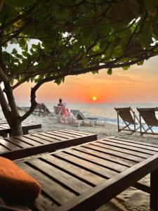 a bench on the beach with a sunset in the background at Windy Waves Kite Beach & Nature Resort in Kalpitiya
