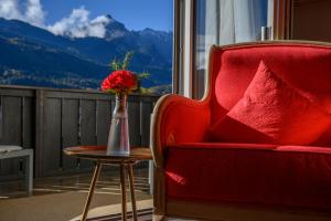 een rode stoel en een vaas met bloemen op een tafel bij Biohotel Garmischer Hof in Garmisch-Partenkirchen
