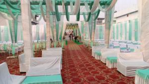 an aisle with white chairs and green and white curtains at Hotel Royal Grand in Dehradun