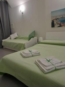 two beds in a room with green sheets and towels at Monteoliveto 5 in Naples