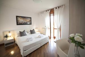 a white bedroom with a white bed and a chair at Roman Holidays all'Eur in Rome