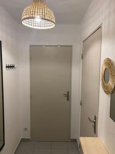 un couloir avec une porte, un miroir et un lustre dans l'établissement Studio fonctionnel quartier faculté St Jérôme, à Marseille