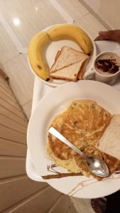 a plate with an omelet and a banana and bread at Hotel Grand Corp Inn, Near Nesco Exhibition Center in Mumbai